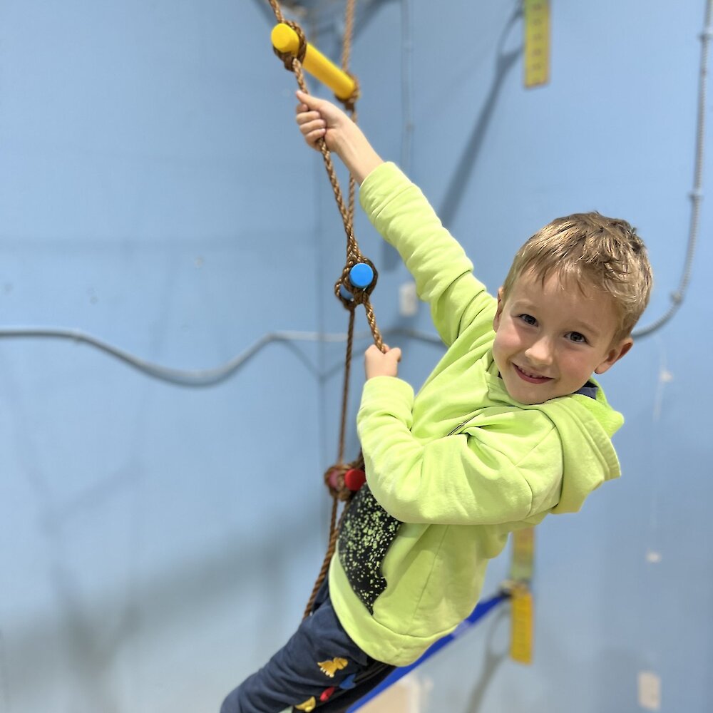 Boy climbing a rope ladder at Zaaz Eatery & Play in Kamloops, BC.