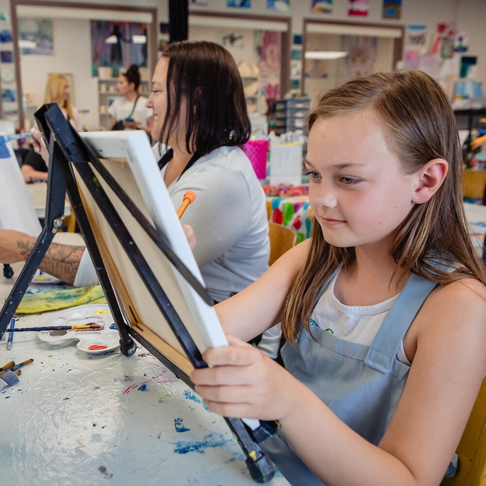 Girl and her mother painting on easels at Kamloops Art Party located on the North Shore on Kamloops, BC.