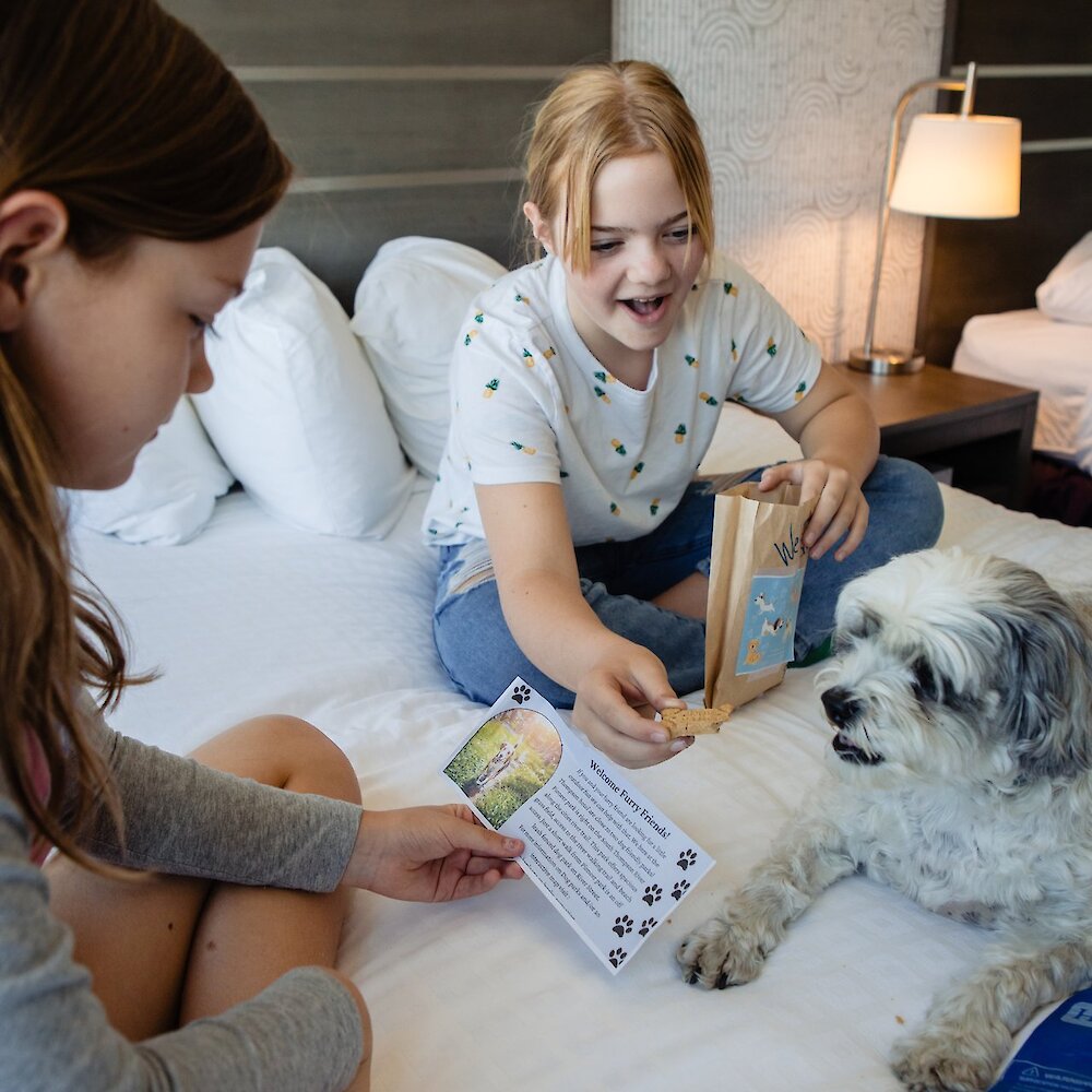 Two girls feeding their dog a treat at the dog-friendly Thompson Hotel in downtown Kamloops, BC.