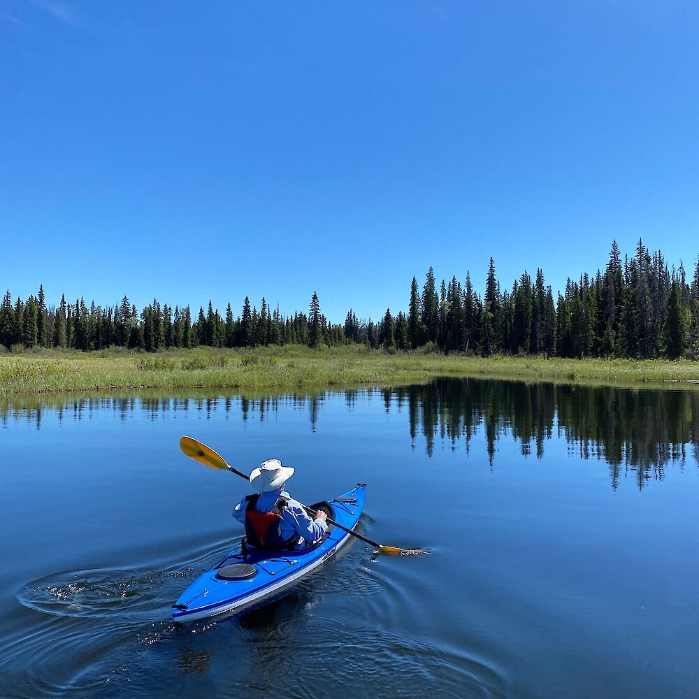 A man Kayaking on Lac Le Jeune, a popular destination for lake paddling near Kamloops, BC.