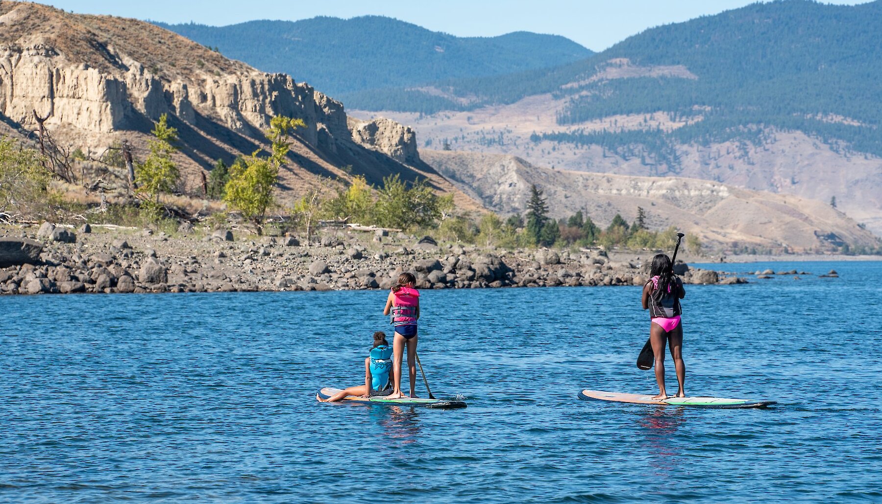 A family stand up paddleboarding on one of the many lakes near Kamloops, BC.