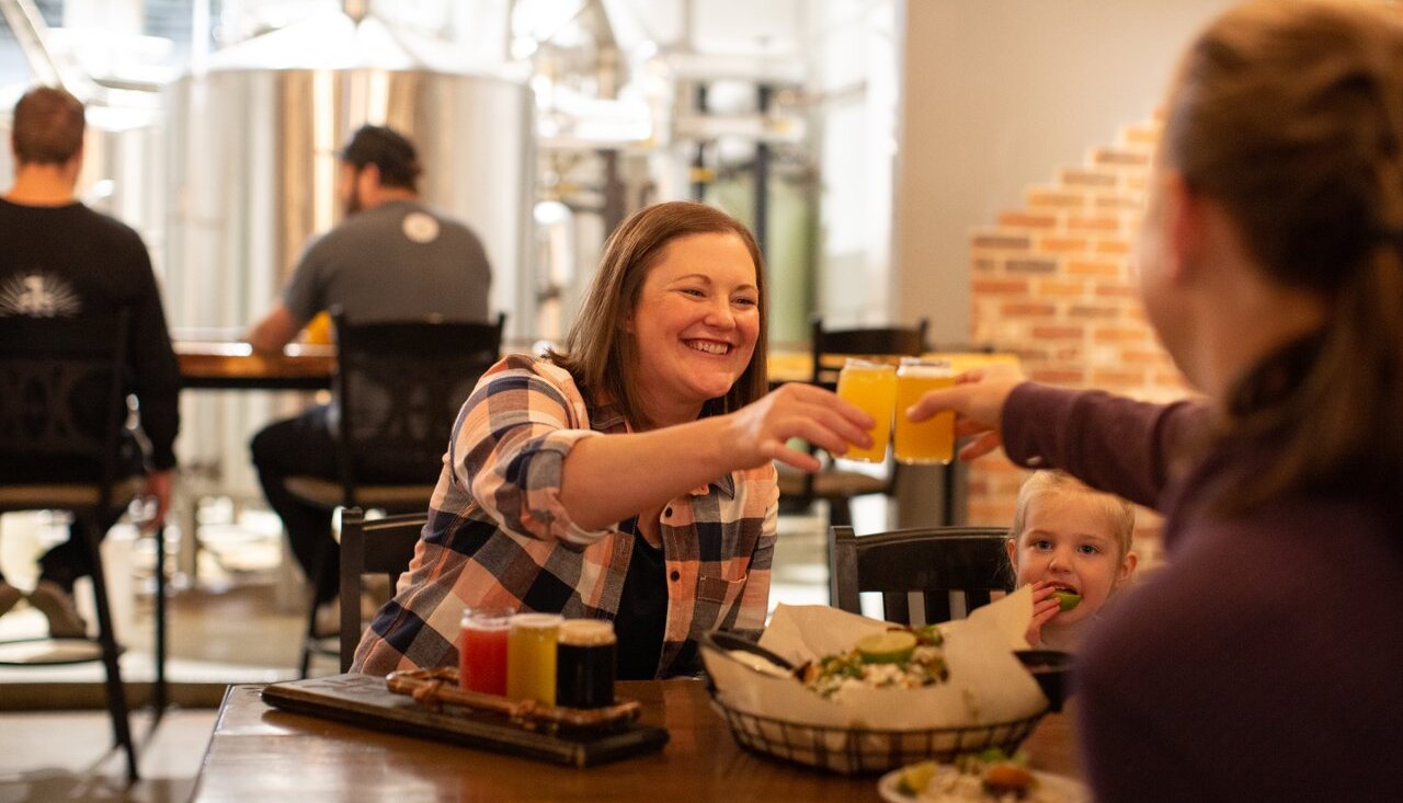 A family toasts while enjoying a beer flight at Iron Road Brewing.