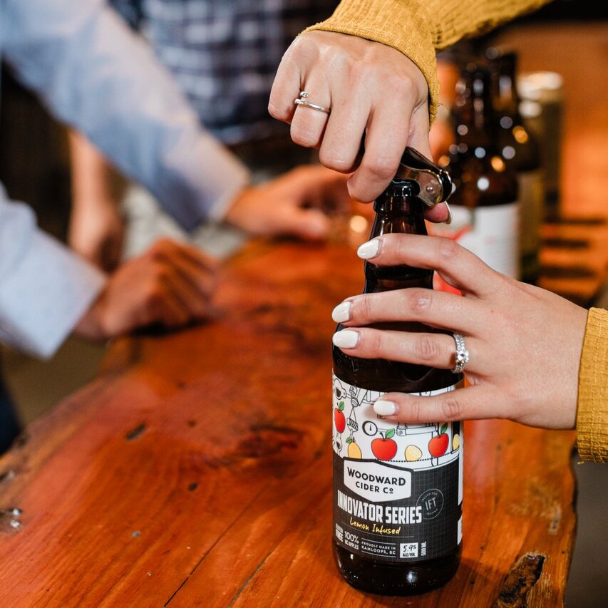 A hand uncaps a bottle of Woodward Cider in Kamloops BC.