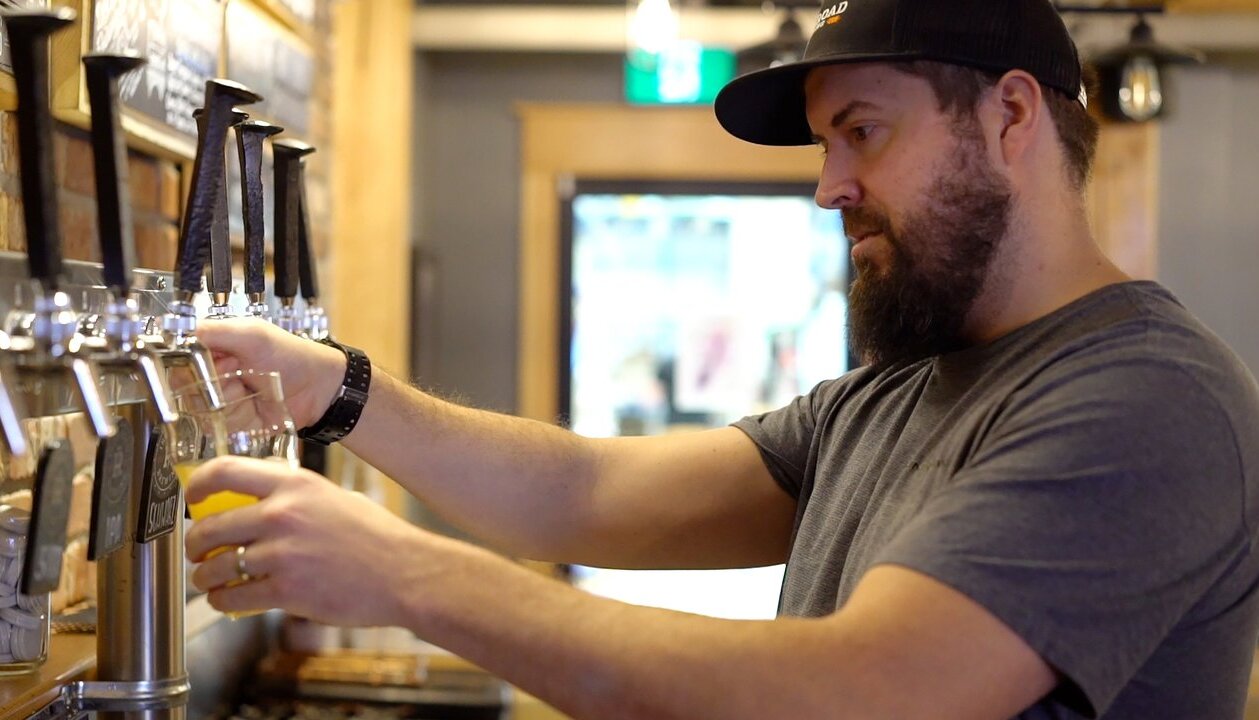 An award-winning brewer at Iron Road in Kamloops BC fills a glass in the taproom.