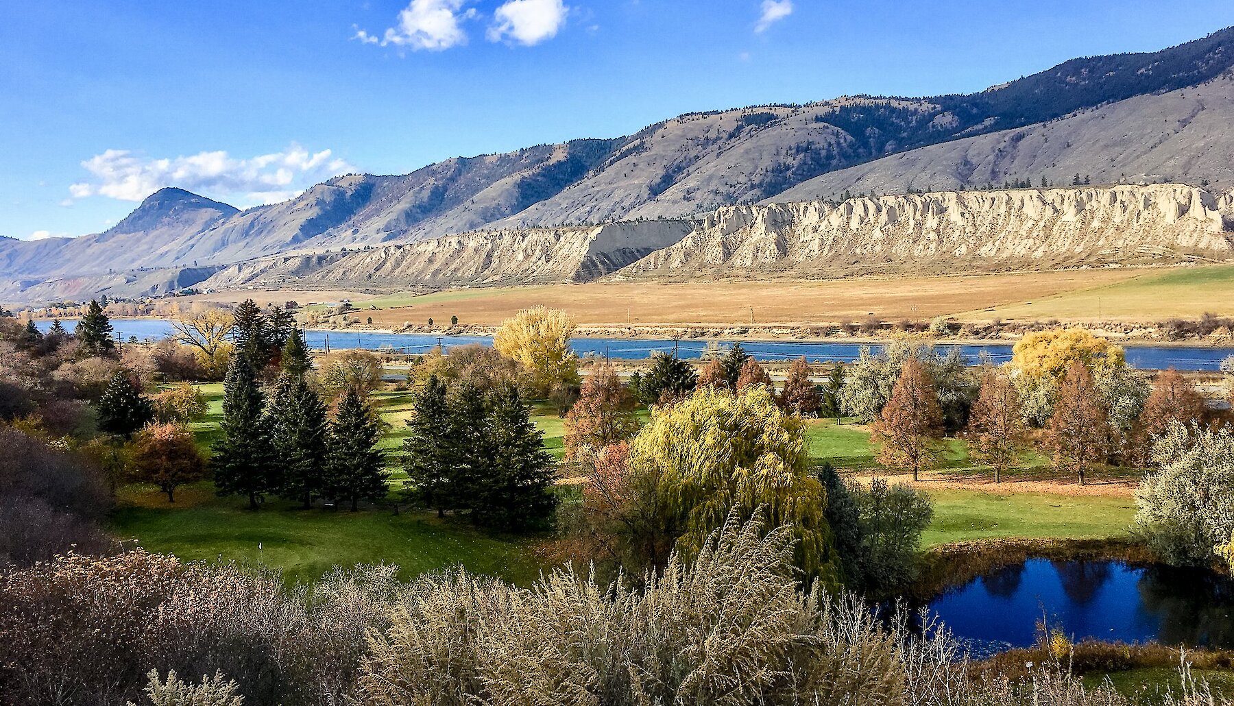 Scenic views of the Pineridge Golf Course with fall tress with geographical bluffs and mountains in the background in Kamloops BC.