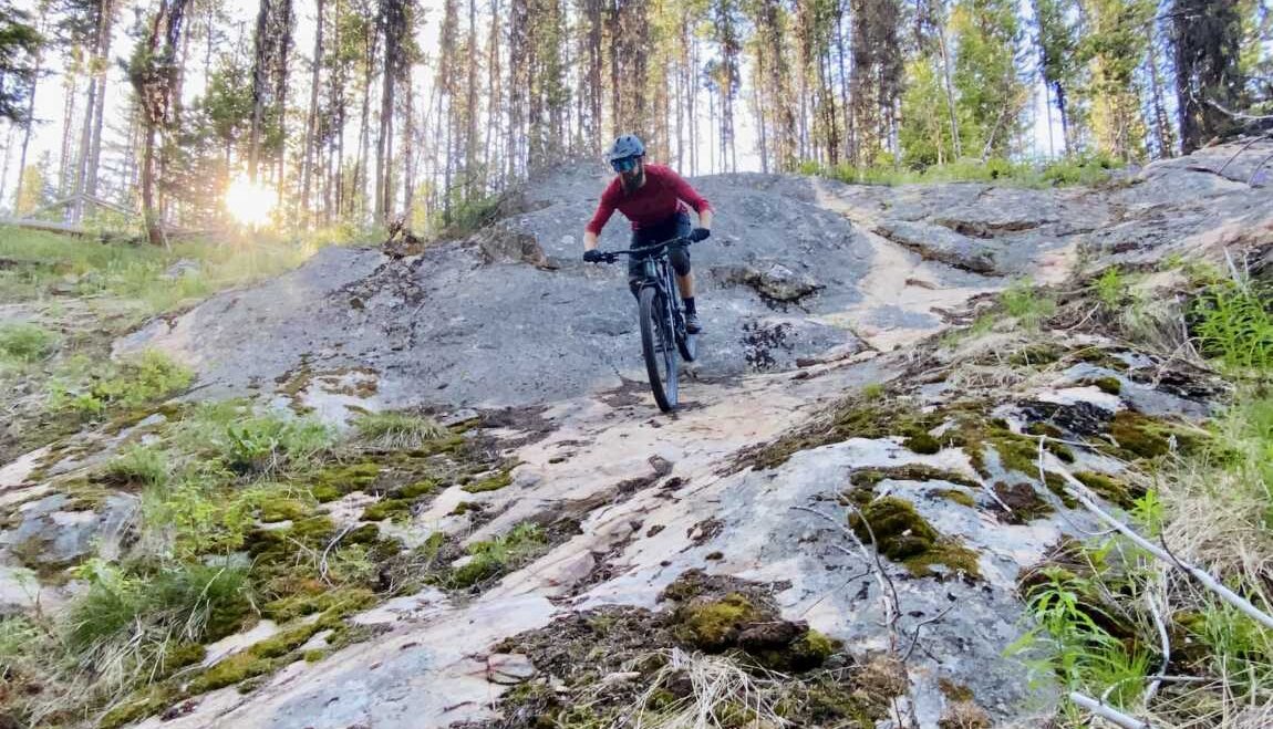 Mountain biker riding down a roadface at Stake Lake in Kamloops, BC.