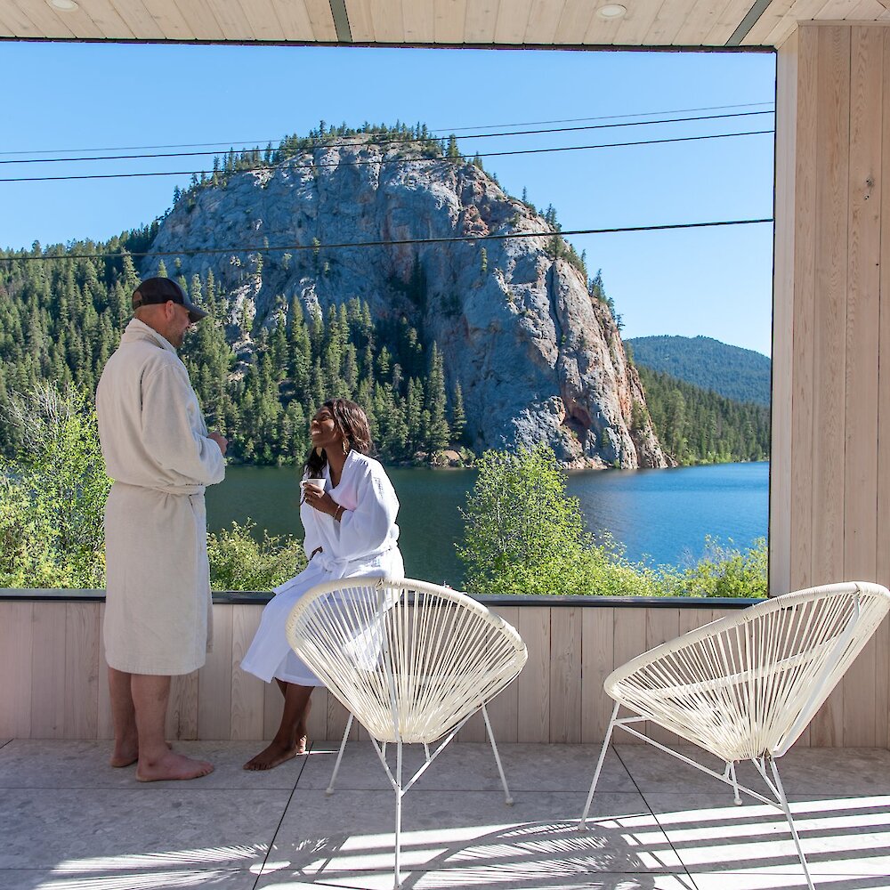 Couple in white robes relaxing with a view of the stunning geological formations and Paul Lake in the background.