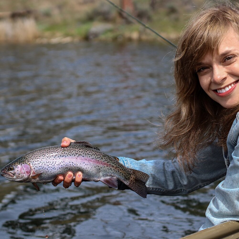 Woman holding a Rainbow Trout caught from her trout fishing in Kamloops, BC.