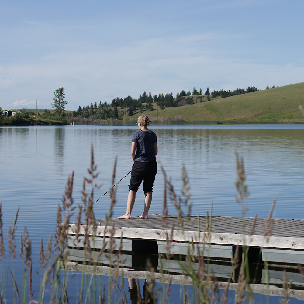 Woman using the fishing dock at a Kamloops area lake in BC.