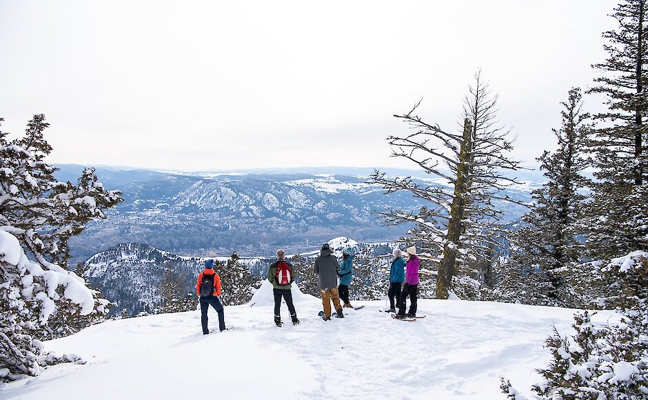 Group of snowshoers admiring the view over the city from Harper Mountain located near Kamloops British Columbia.