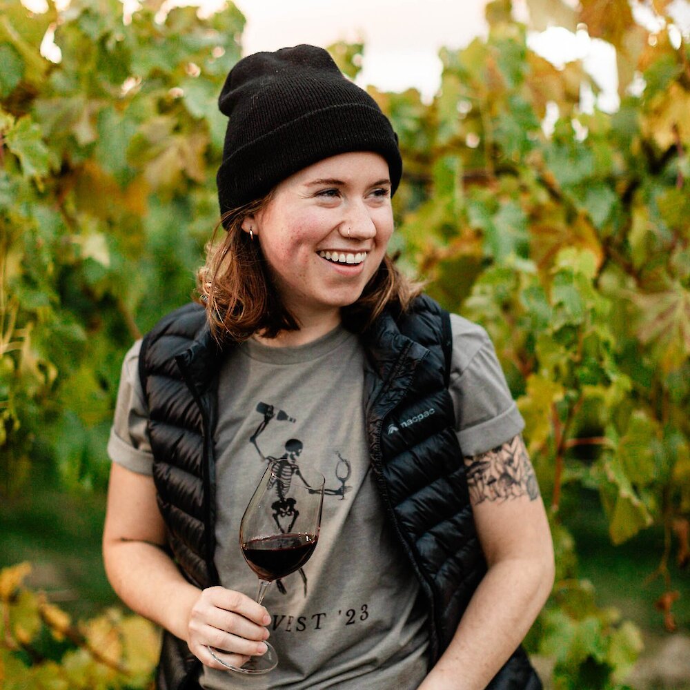 Woman with a glass of red wine in the autumn coloured vineyard at Monte Creek Winery near Kamloops, BC.