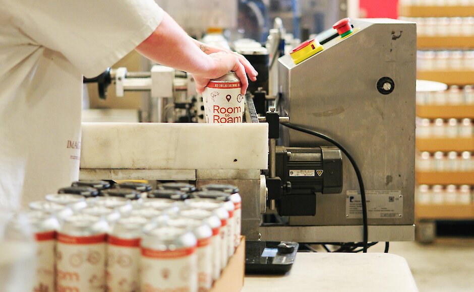 Staff pulling a can of the Room to Roam White IPA off the production line at Red Collar Brewing in Kamloops, British Columbia.