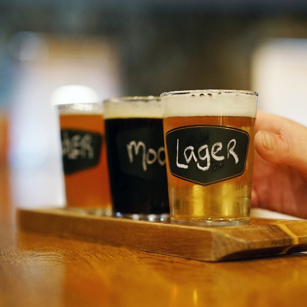 A hand reaching for a pint of the Noble Pig lager at the brewhouse located in downtown Kamloops, British Columbia.