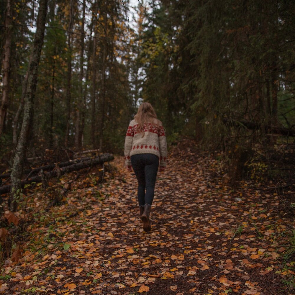 A woman walking along a leafy autumn hiking trail at Isobel Lake near Kamloops, British Columbia.