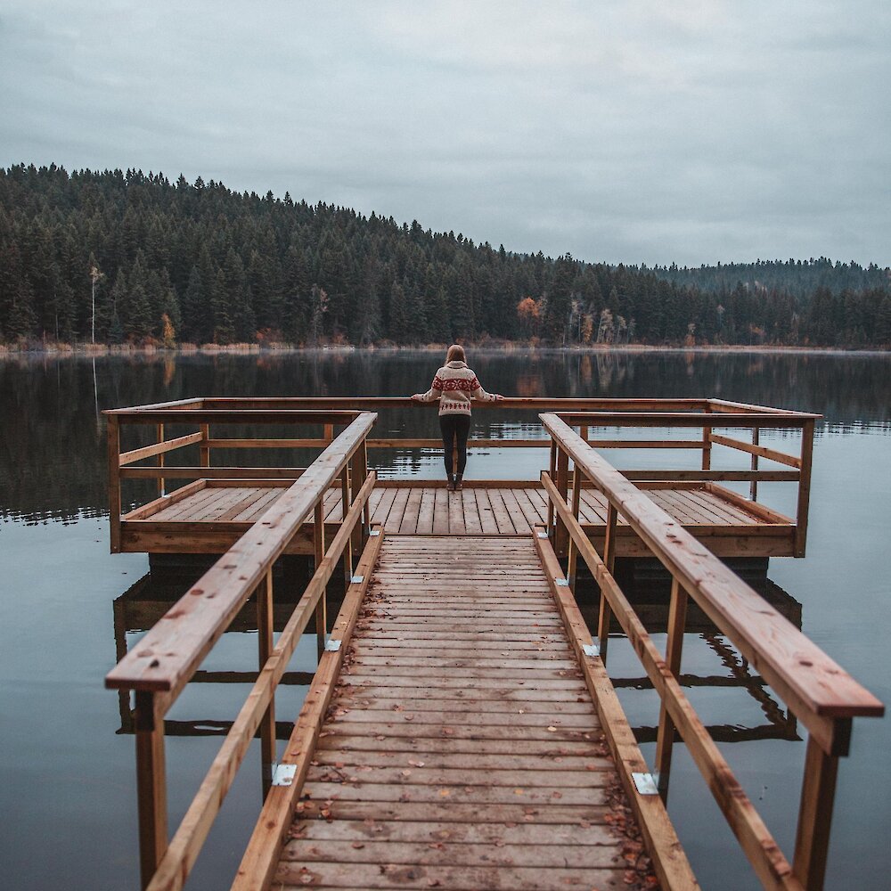 A woman admiring the view over Isobel Lake from the dock located near Kamloops, BC.