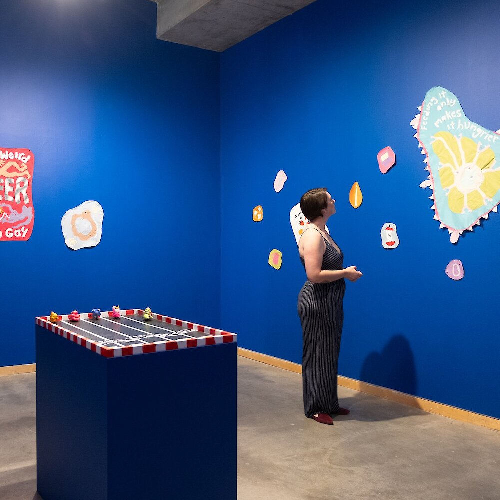 Woman admiring the new exhibit at the Kamloops Art Gallery Opening Reception for Adrian Romeo: Every Day is a Day at the Races When You're Mentally and Physically Ill.