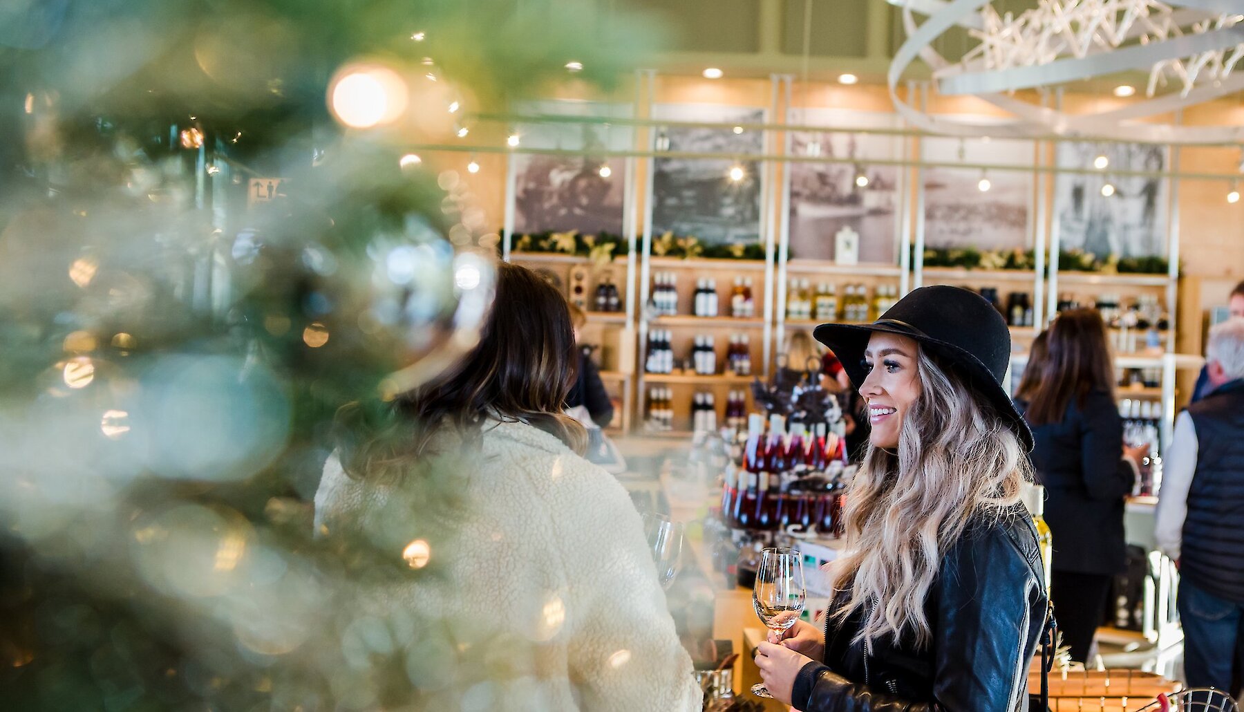 A woman enjoying a glass of complimentary wine in the festive Monte Creek Winery tasting room at the Sip and Shop event.