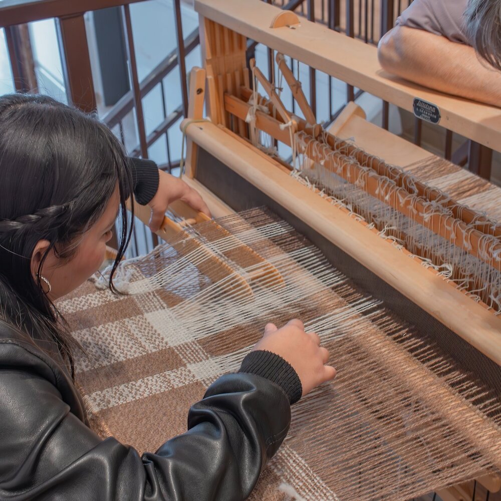 A woman interacts with the weaving display at the Common Thread exhibit at the Kamloops Museum & Archives (KMA) located in downtown Kamloops, BC.