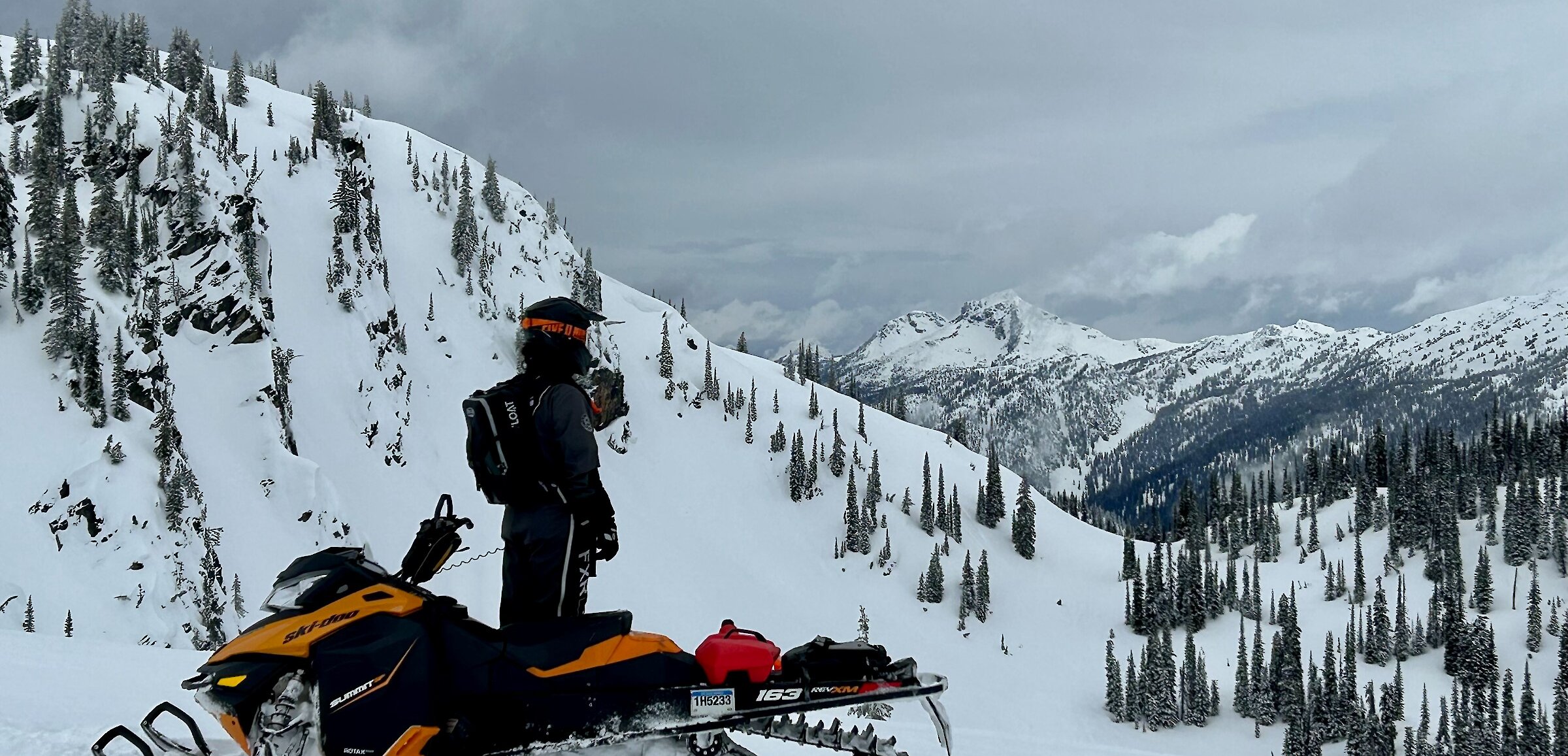 Snowmobile rider admiring the view of the snowy landscape while out exploring in the Thompson Valley, BC.