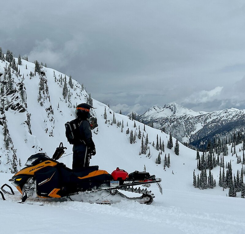 Snowmobile rider admiring the view of the snowy landscape while out exploring in the Thompson Valley, BC.