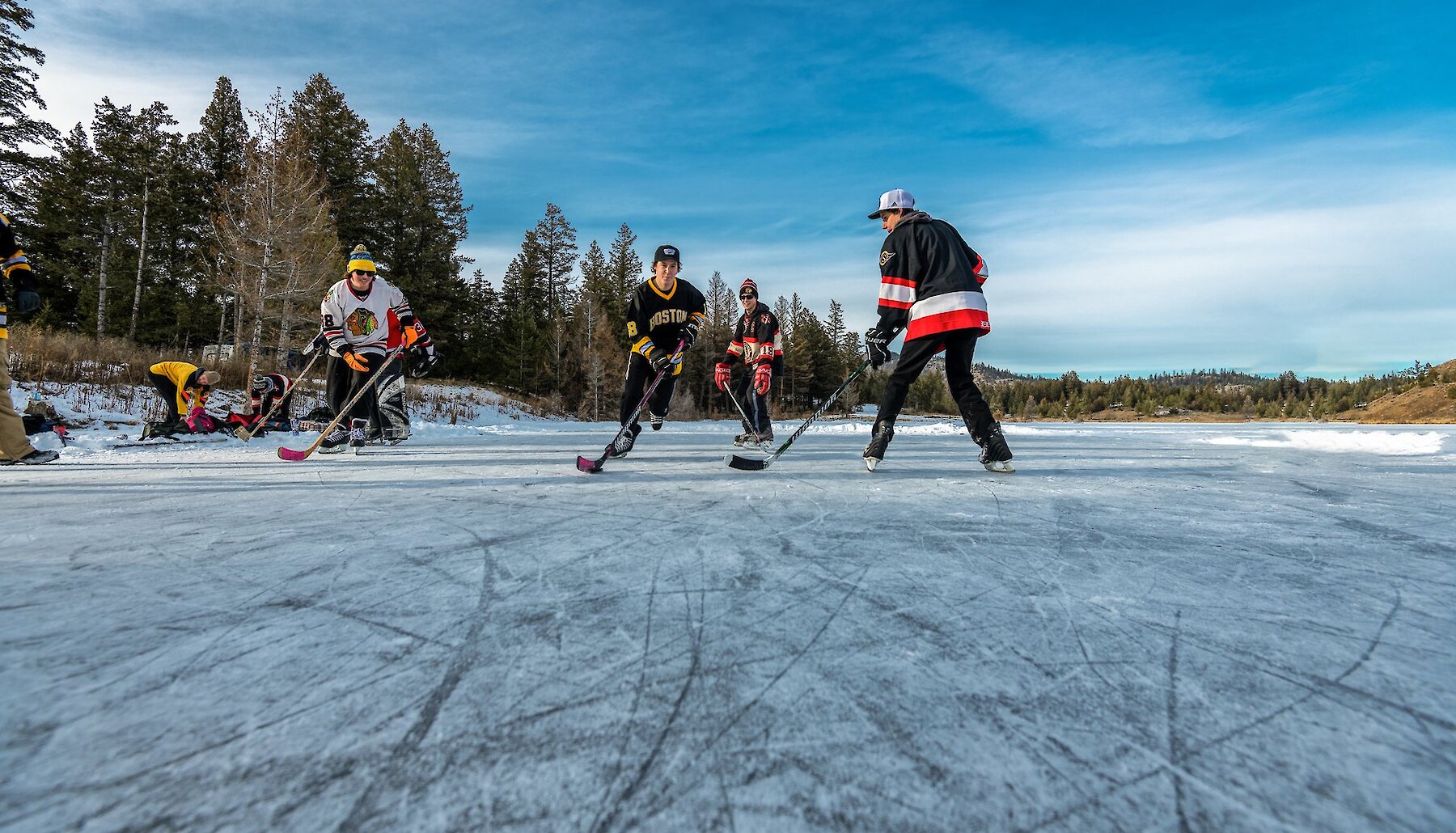 A group of hockey players ice skating at the beautiful outdoor ice rink on Inks Lake located near Kamloops, British Columbia.