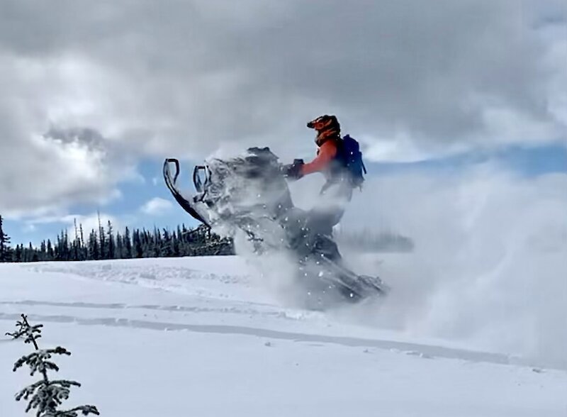 Kamloops snowmobile riding getting air on his sled through the fresh powder.