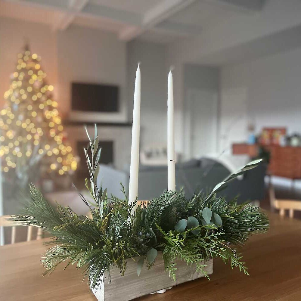 Floral centrepiece from Fern and Fond on a dining table with a Christmas tree in the background.