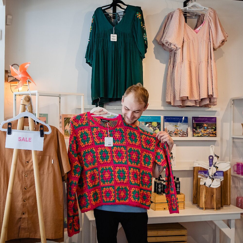 A man hold up a sweater as he shops at the Crooked Crown store located in Kamloops, BC