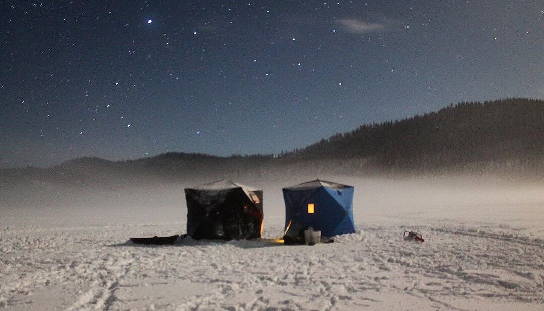 Ice fishing huts on a lake near Kamloops BC, under a clear starry sky.