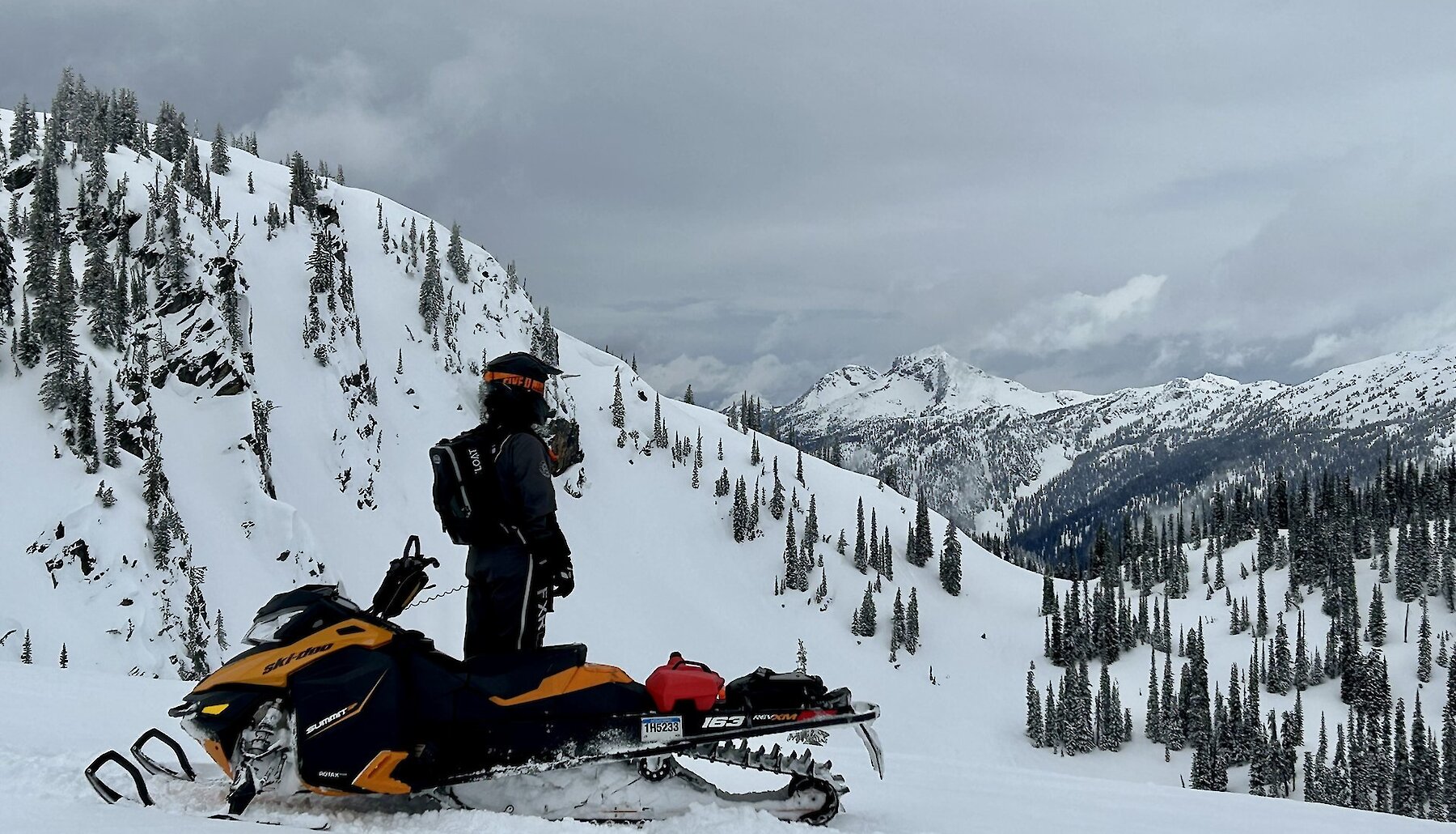 Sledder admiring the natural beauty of the Thompson Valley during a snowmobile tour near Kamloops, BC.