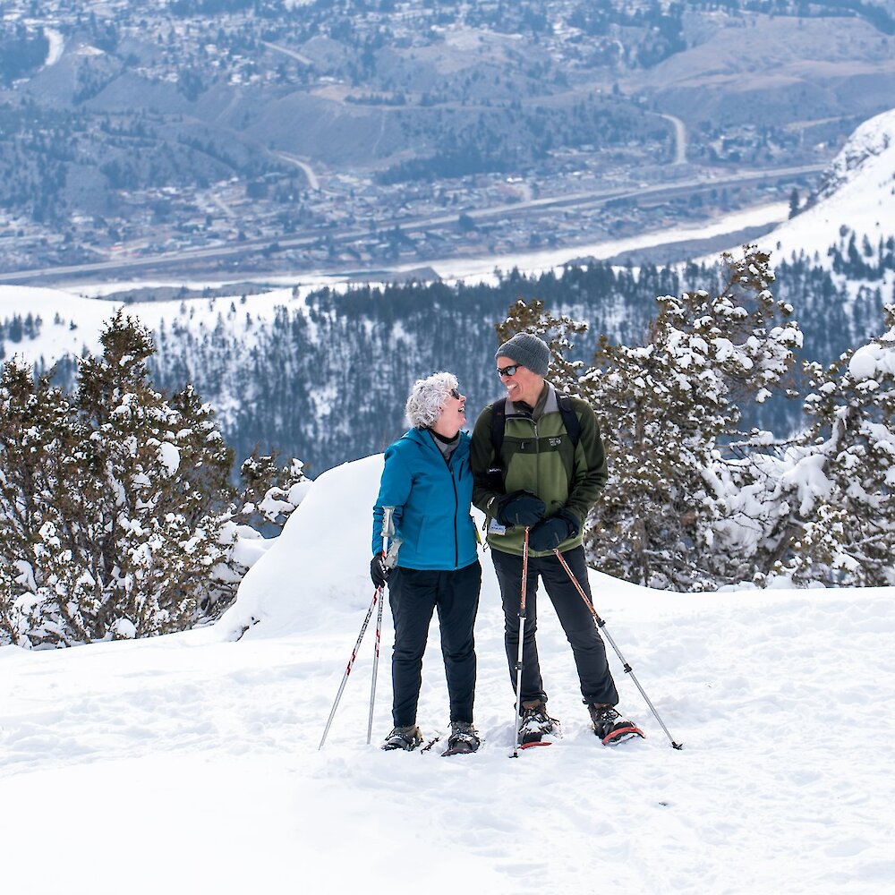 Snowshoeing couple smile at each other at the summit of Harper Mountain.