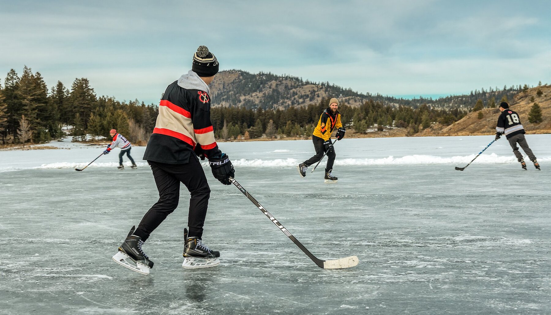 Skaters playing hockey on the outdoor frozen rink at Inks Lake near Kamloops, BC.