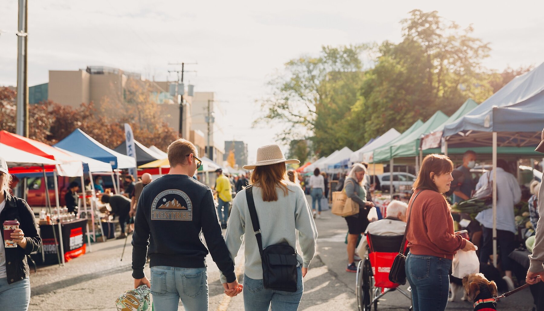 A couple holds hands as they walk through the Kamloops Farmers Market on a sunny day in downtown Kamloops, BC.