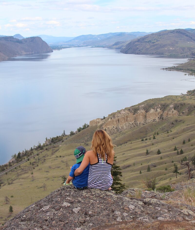 A Mother and son admiring the view over Kamloops Lake from a hiking viewpoint in Kamloops, BC.