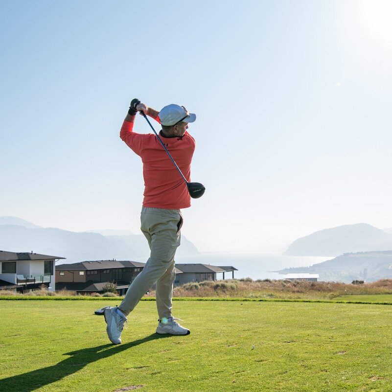 Golfer swinging his club on a sunny day at Tobiano golf course located in Kamloops, BC.