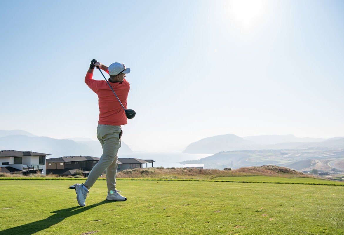 Golfer swinging his club on a sunny day at Tobiano golf course located in Kamloops, BC.