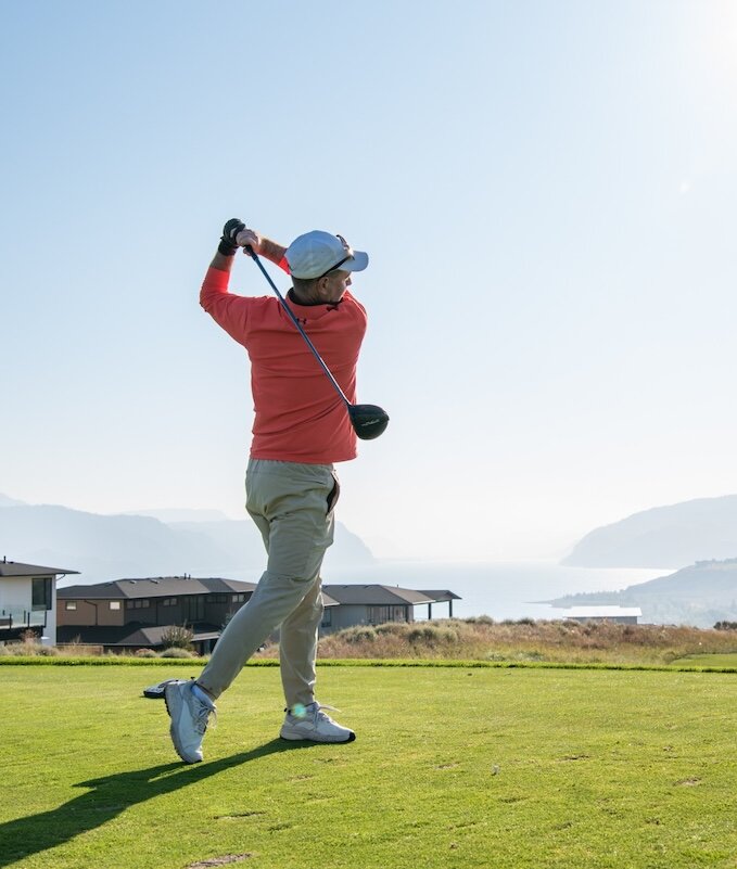 Golfer swinging his club on a sunny day at Tobiano golf course located in Kamloops, BC.