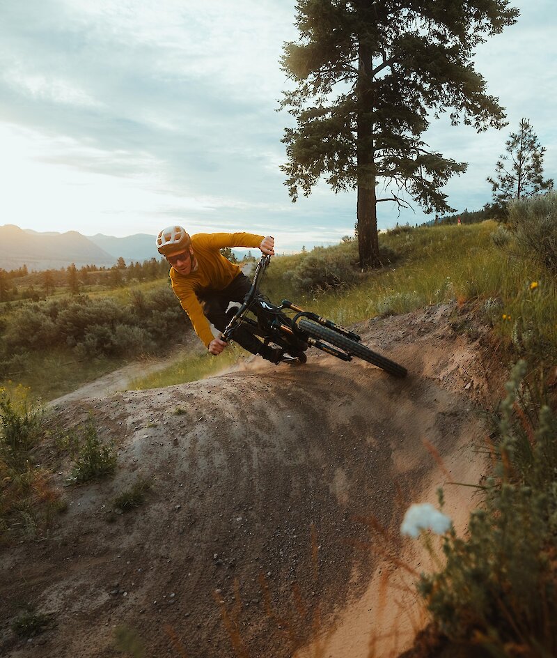 Pro mountain biker Matt Hunter riding a trail at the Kamloops Bike Ranch surrounded by flowers and greenery in Kamloops, BC.