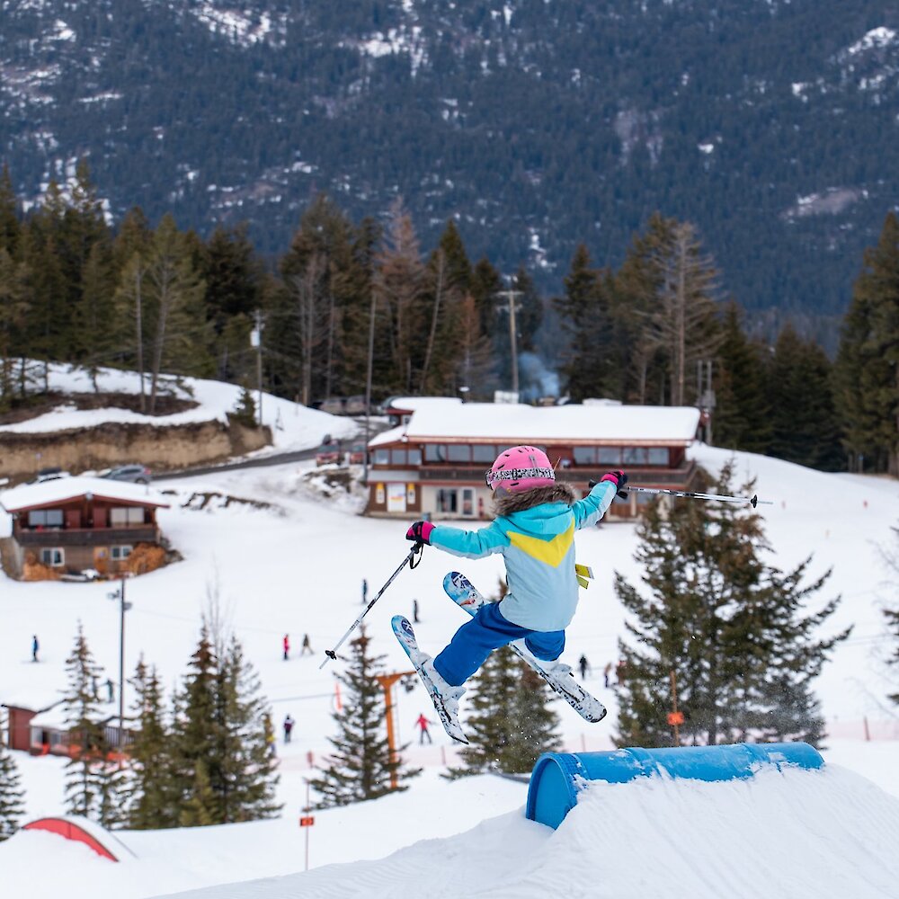 A little skier takes a ski jump at Harper Mountain ski and snowboard near Kamloops, BC.