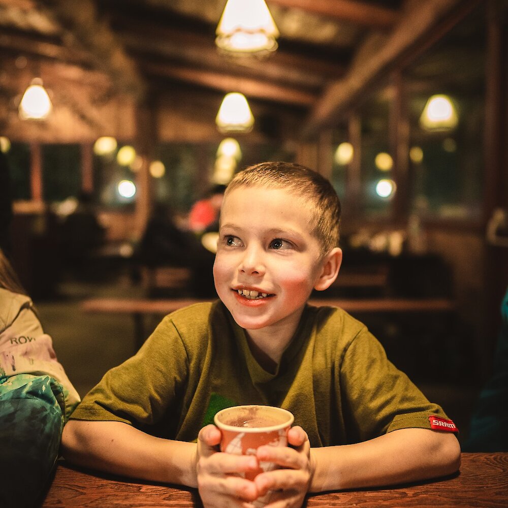 A boy enjoying hot chocolate in the cozy lodge at Harper Mountain ski resort near Kamloops, BC.