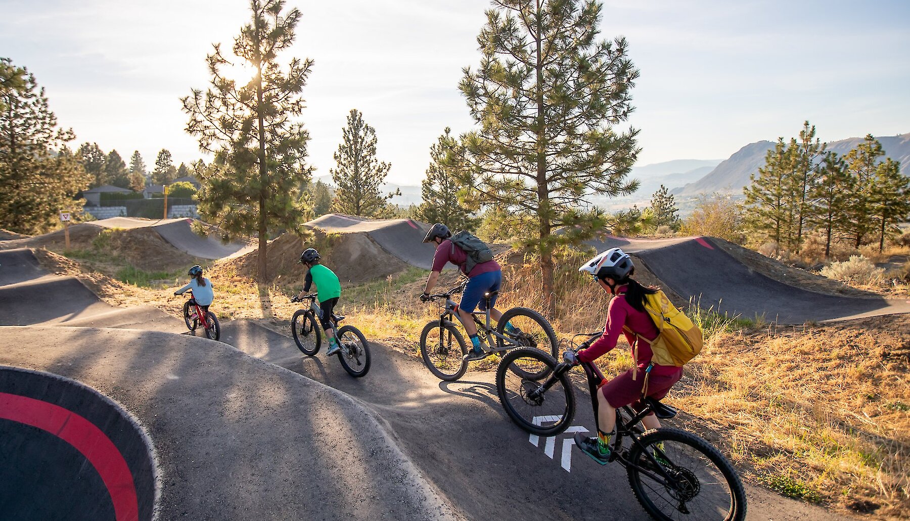 The entire family riding their bikes along the all wheel pump track located at the Bike Ranch in Kamloops, BC.