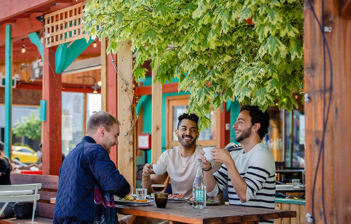 Three people eating at an outdoor patio restaurant table in Kamloops.