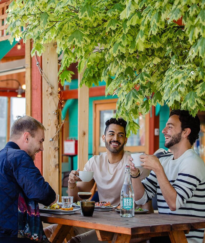 Three people eating at an outdoor patio restaurant table in Kamloops.