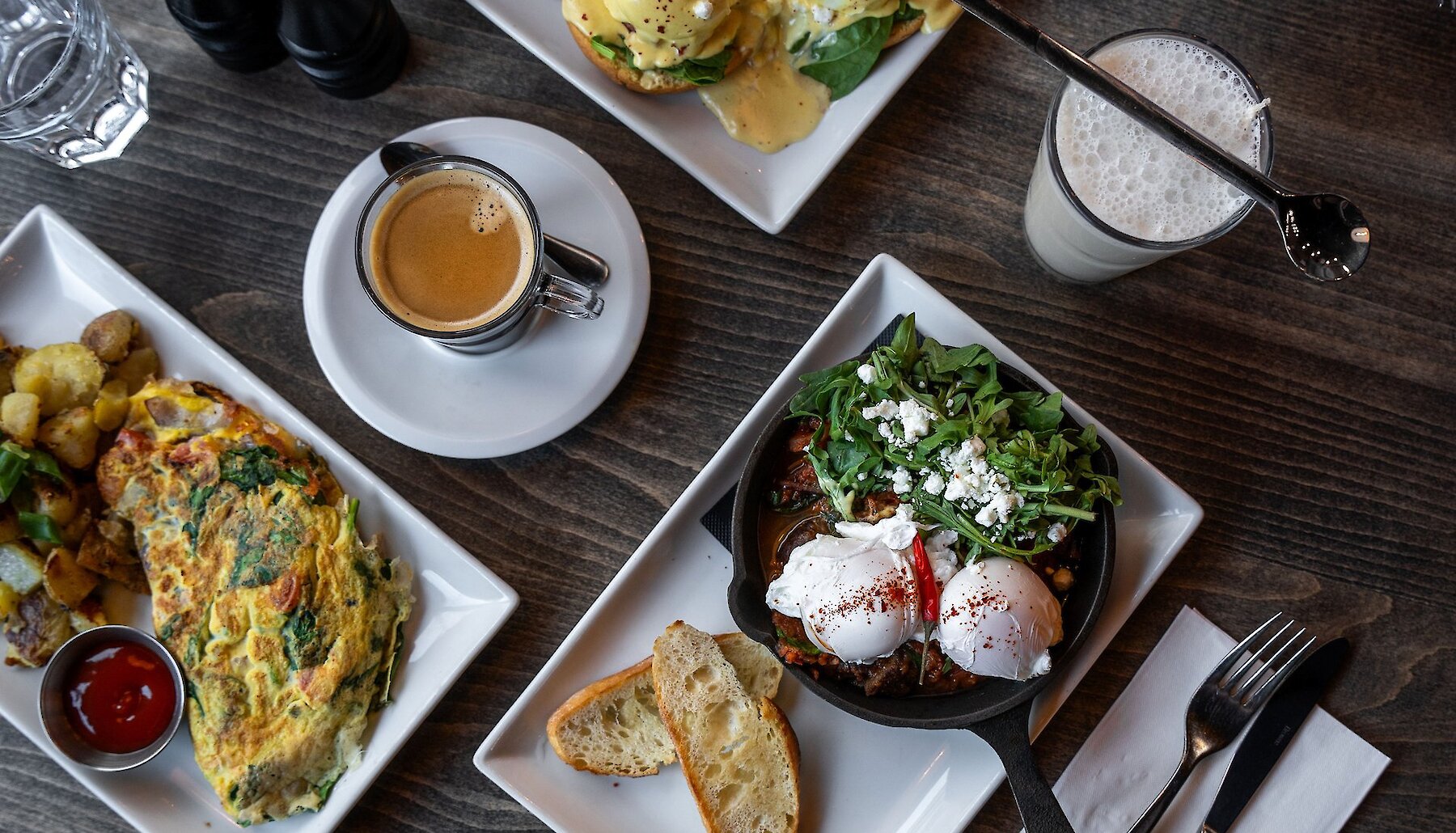 A brunch spread is set out on a table, complete with coffee, water, milk, and several egg dishes.