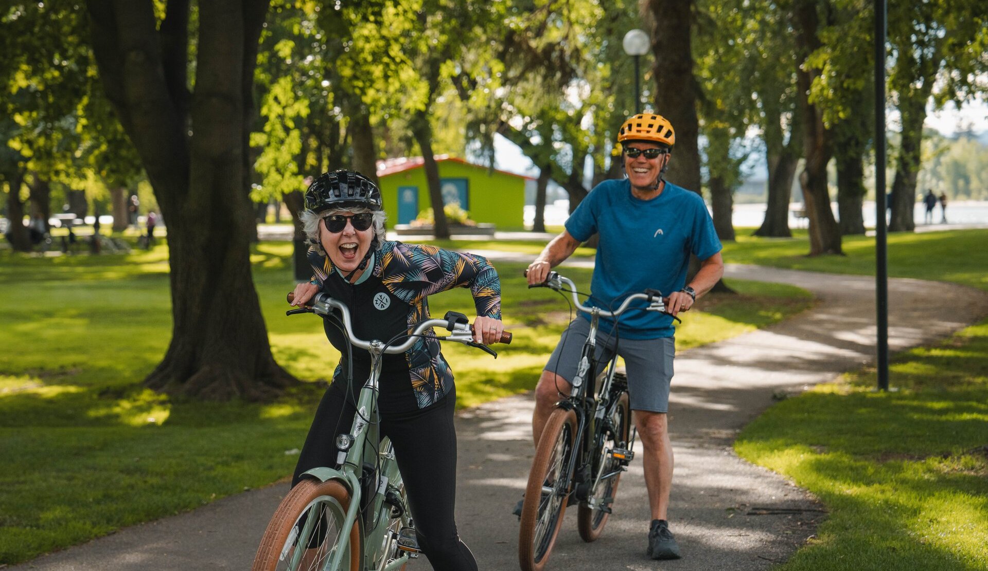 A couple of cyclists on cruiser bikes laugh while riding.